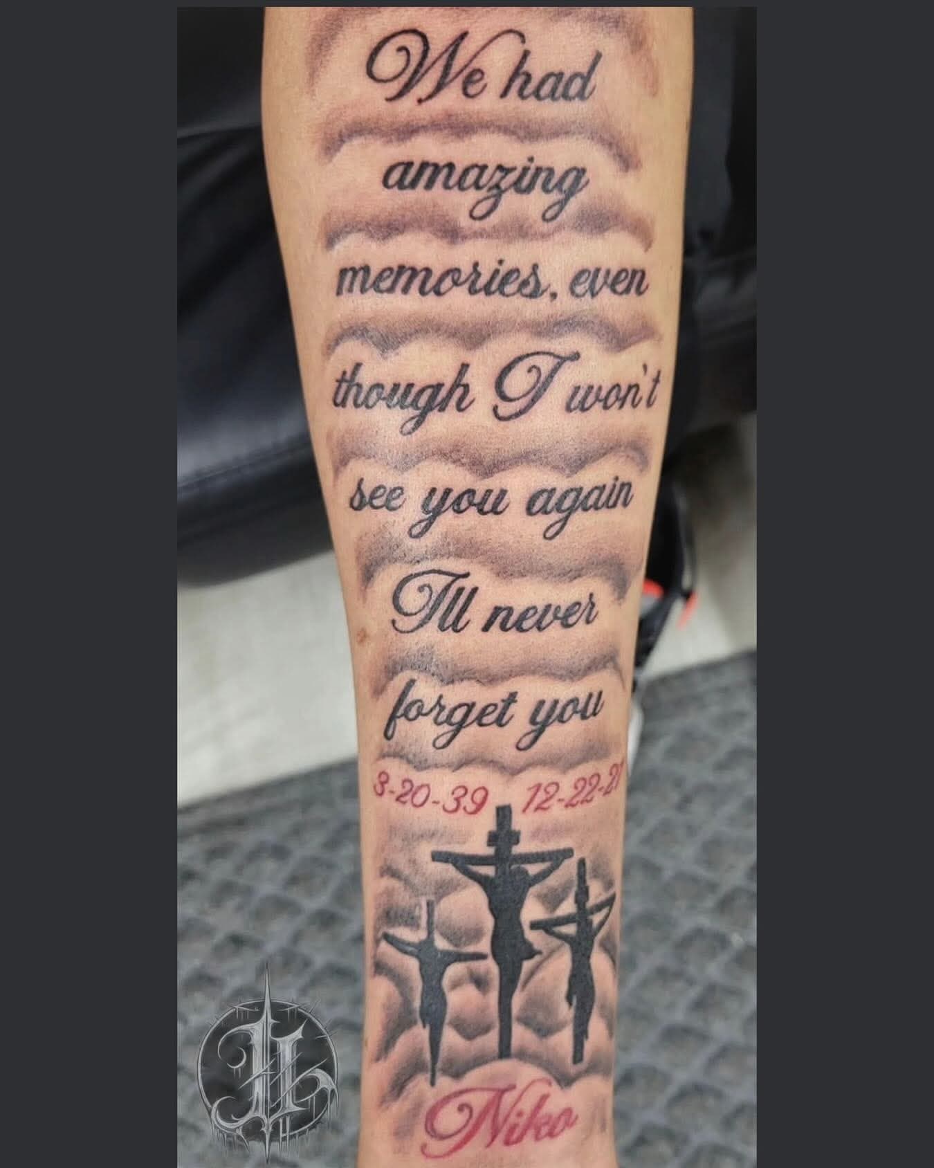 Black-and-grey memorial forearm tattoo: script lettering through clouds above a three-crosses Calvary scene with dates and the name Niko.